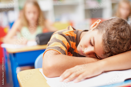 Boy, student and sleeping in classroom at elementary school with burnout, tired and bored. Learner, kid and exhausted with resting on desk or table for education, learning and brain development