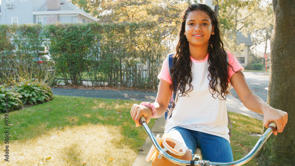 Obraz premium Portrait Of Girl Wearing Backpack Riding Her Bike Along Suburban Street On Her Way To School