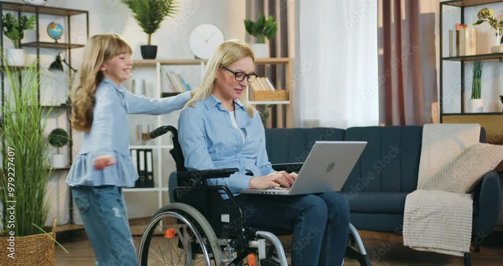 Mother which sitting in wheelchair after accident and working on computer girl running up to her at home Mother which sitting in wheelchair after accident and working on computer girl running up to her at home