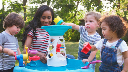 Konstfotografi Mother And Young Children Playing With Water Table In Garden