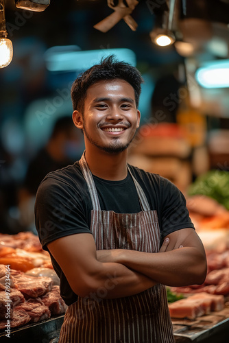 A portrait of a young male butcher standing confidently inside his market photo