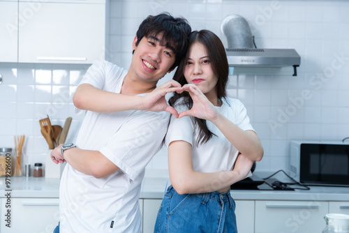 Obraz na płótnie Happy portrait of loving young asian of having fun standing a cheerful heart shaped hands preparing food and enjoy cook cooking bread while standing on a kitchen Condo life or home w salonie