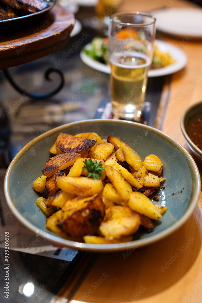 Roasted potatoes in a dish next to a glass of bear. Top, close up shot, shallow depth of field, no people Roasted potatoes in a dish next to a glass of bear. Top, close up shot, shallow depth of field, no people