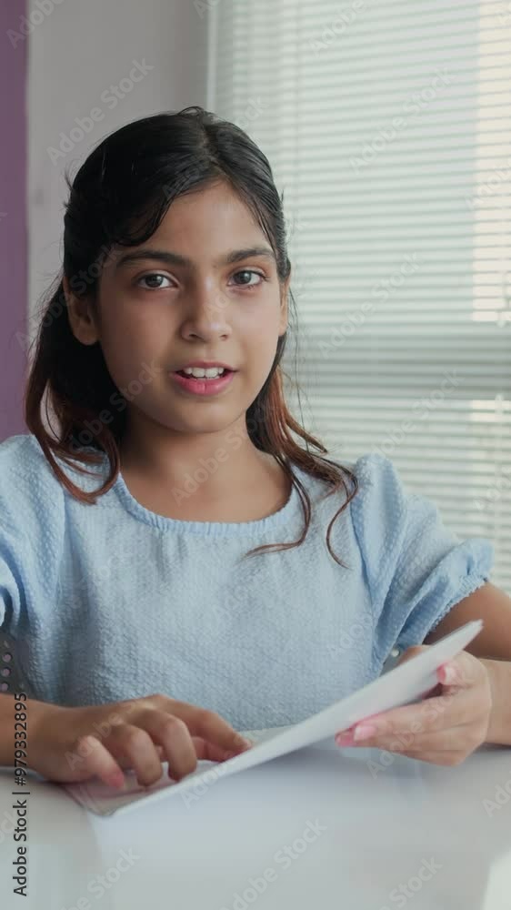 Vertical POV of Indian schoolgirl pronouncing sounds when sitting at table during logopedic session Vertical POV of Indian schoolgirl pronouncing sounds when sitting at table during logopedic session