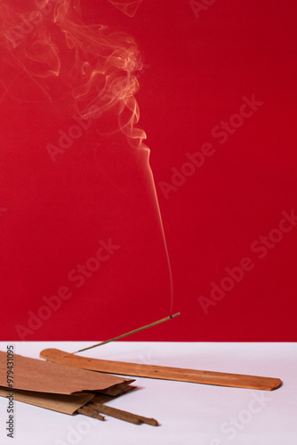Obraz na plátně An incense stick smokes on a red background