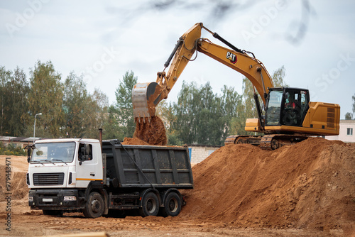 excavator at work on sand putting sand at truck