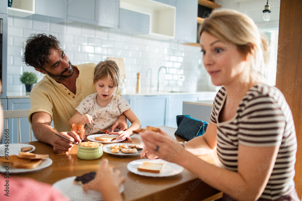 Family having breakfast together in kitchen with parents and child making toast Family having breakfast together in kitchen with parents and child making toast