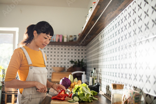 Asian woman chopping vegetables in kitchen for healthy meal prep