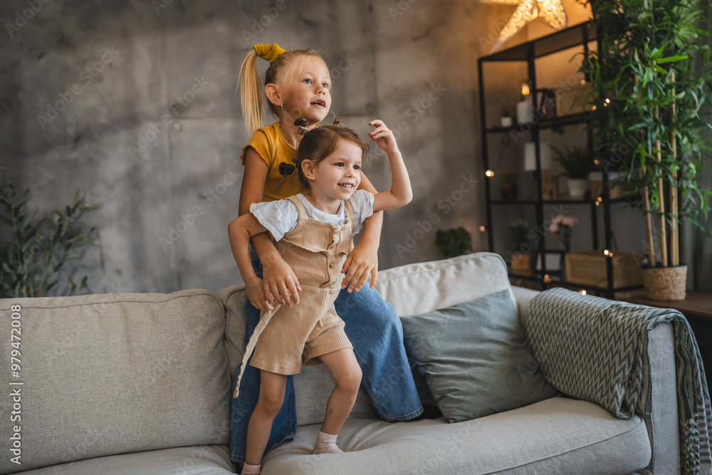 Obraz premium Two young girls play together on the sofa at home