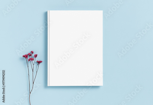 Mockup of a white hardcover book on a blue background dried gypsophila flower. Blank template for your design and advertising in a minimalist style. Flat lay