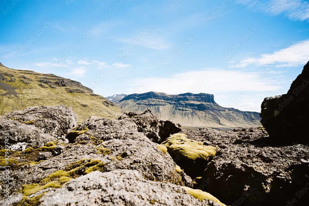 Mossy lava fields and a blue-clouded sky with volcanic mountains Mossy lava fields and a blue-clouded sky with volcanic mountains