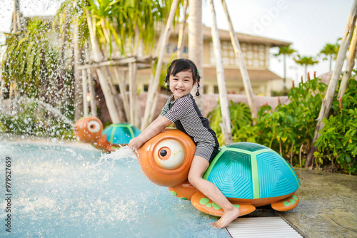 Asian cute little girl having fun with riding a spraying water turtle in the water park.