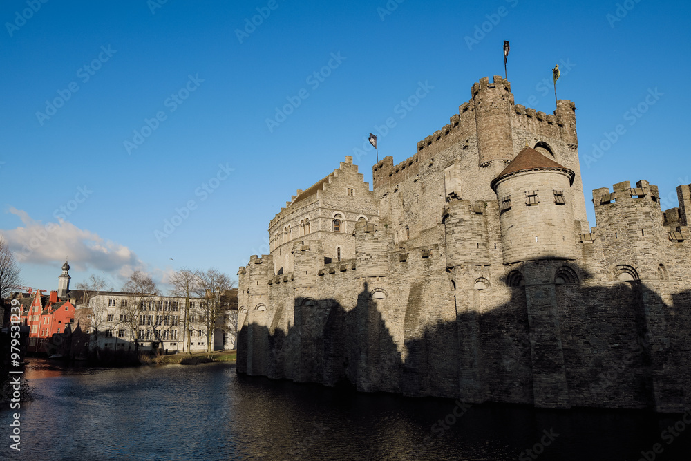 Obraz premium Explore the historic Gravensteen Castle by the river in Ghent, Belgium under a clear blue sky