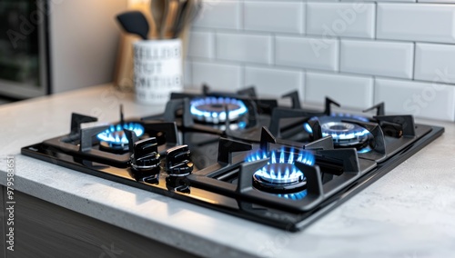 Modern gas stove with blue flames on a sleek kitchen countertop, showcasing a contemporary design against a tiled backsplash