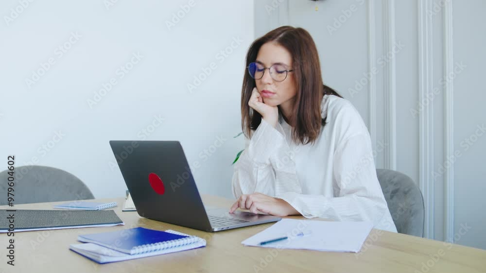 A Dedicated, Focused Professional Engaged in Remote Work on a Sleek Laptop Surrounded by Notes in a Stylish and Minimalistic Office Environment. She is tired and closes her laptop A Dedicated, Focused Professional Engaged in Remote Work on a Sleek Laptop Surrounded by Notes in a Stylish and Minimalistic Office Environment. She is tired and closes her laptop