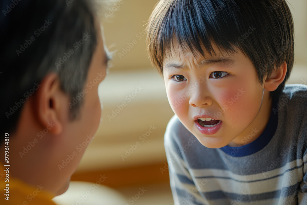 Young boy with flushed cheeks is talking to his father, looking upset and angry Young boy with flushed cheeks is talking to his father, looking upset and angry