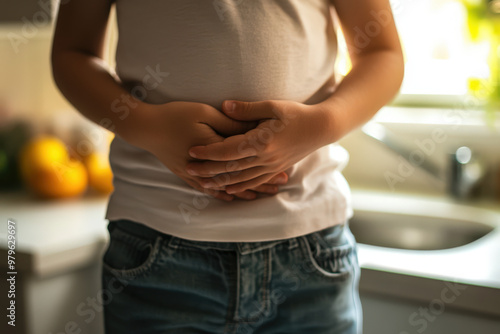 Child experiencing intense abdominal pain, standing in the kitchen