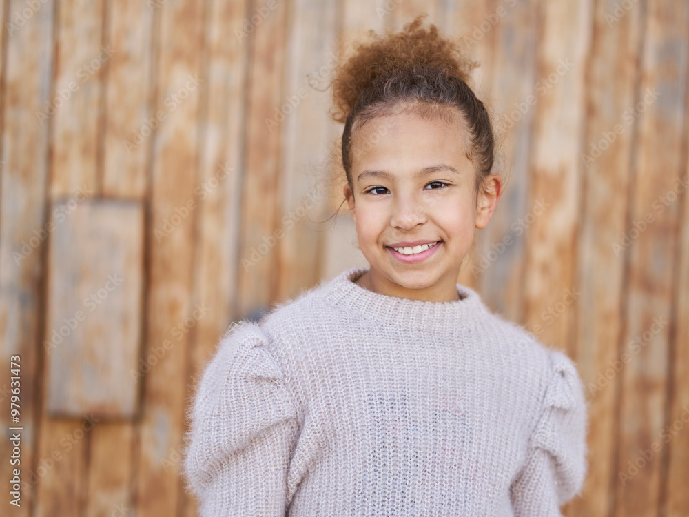 A young girl with a big smile on her face is wearing a sweater and has her hair in a bun A young girl with a big smile on her face is wearing a sweater and has her hair in a bun