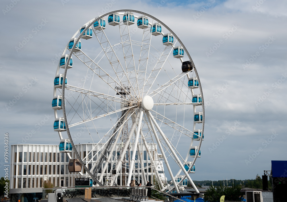 Large ferris wheel rotating under cloudy sky on waterfront. Helsinki Finland Large ferris wheel rotating under cloudy sky on waterfront. Helsinki Finland