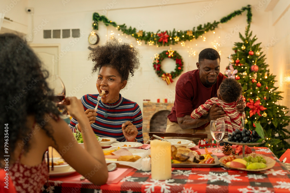 A joyful family gathers around the dinner table celebrating Christmas. The father, dressed in a Santa hat, gives a gift to the child, while everyone smiles with warmth and festive decorations. A joyful family gathers around the dinner table celebrating Christmas. The father, dressed in a Santa hat, gives a gift to the child, while everyone smiles with warmth and festive decorations.
