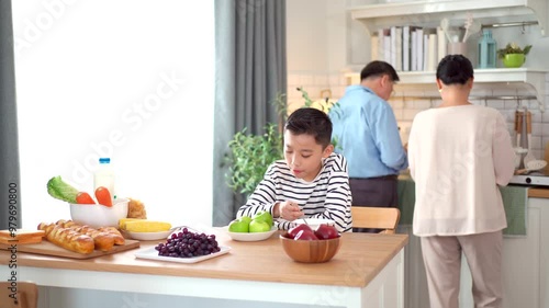 Happy Asian family with farther, mother, and son are enjoy eating a breakfast together in kitchen,  photo