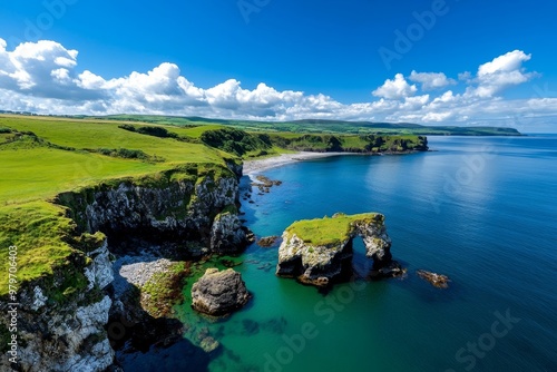 British Isles coastline along Antrim Coast, with rolling green hills meeting the rocky shore and the blue sea beyond