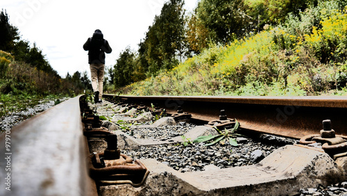 A traveler walking along old railroad tracks photo