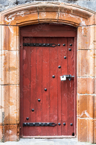 red wooden entrance door covered with iron photo