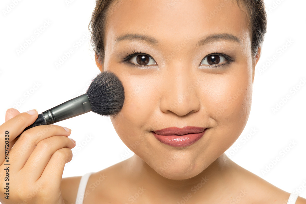 Closeup portrait of a young Asian woman applying blush. Closeup portrait of a young Asian woman applying blush.