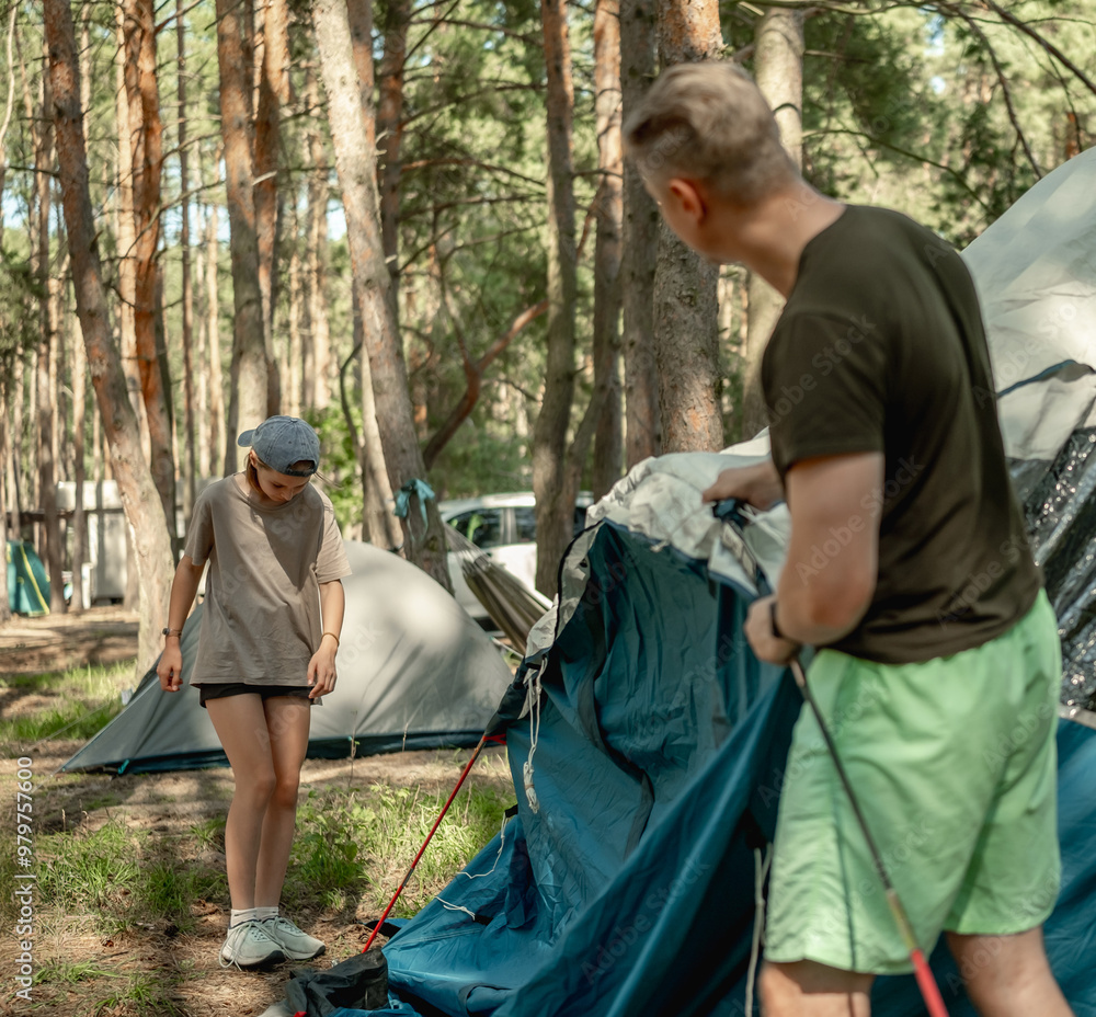 Father And Daughter Setting Up A Tent While Camping In The Forest Father And Daughter Setting Up A Tent While Camping In The Forest