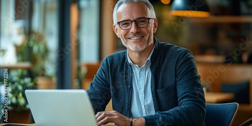 Smiling businessman in his thirties working at a desk with a laptop and digital tablet