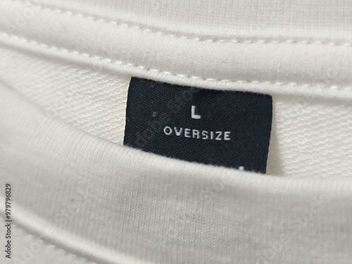 Close up of white t-shirt's round neck collar. Size L oversize t-shirt label tag. Mock up for clothing design photo