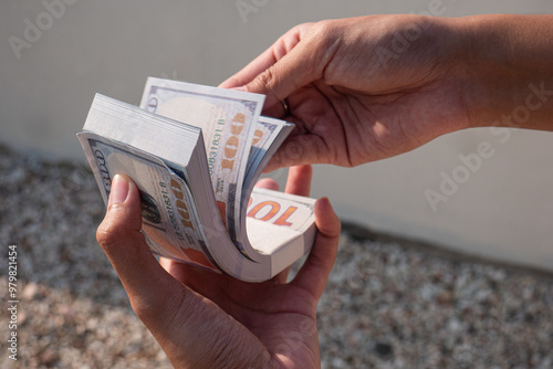 close up of a woman's hand holding a lot of 100 dollar bills. counting 100 dollar bills