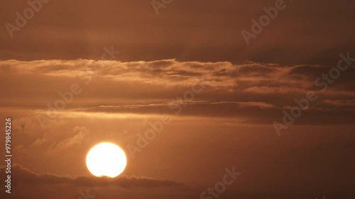 Time lapse cloudscape with sun rising up from morning to day on a warm lit sky.