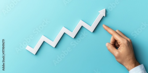 In this picture, a businessman is pointing at an upward trending graph against a blue background.