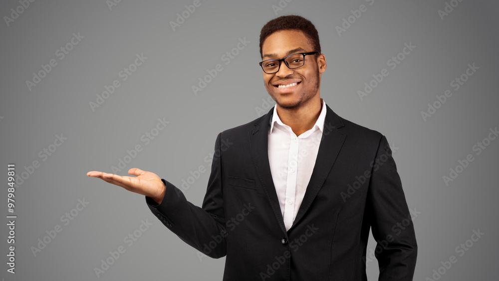 Smiling black man demonstrating something on his empty palm, white studio background, copyspace Smiling black man demonstrating something on his empty palm, white studio background, copyspace