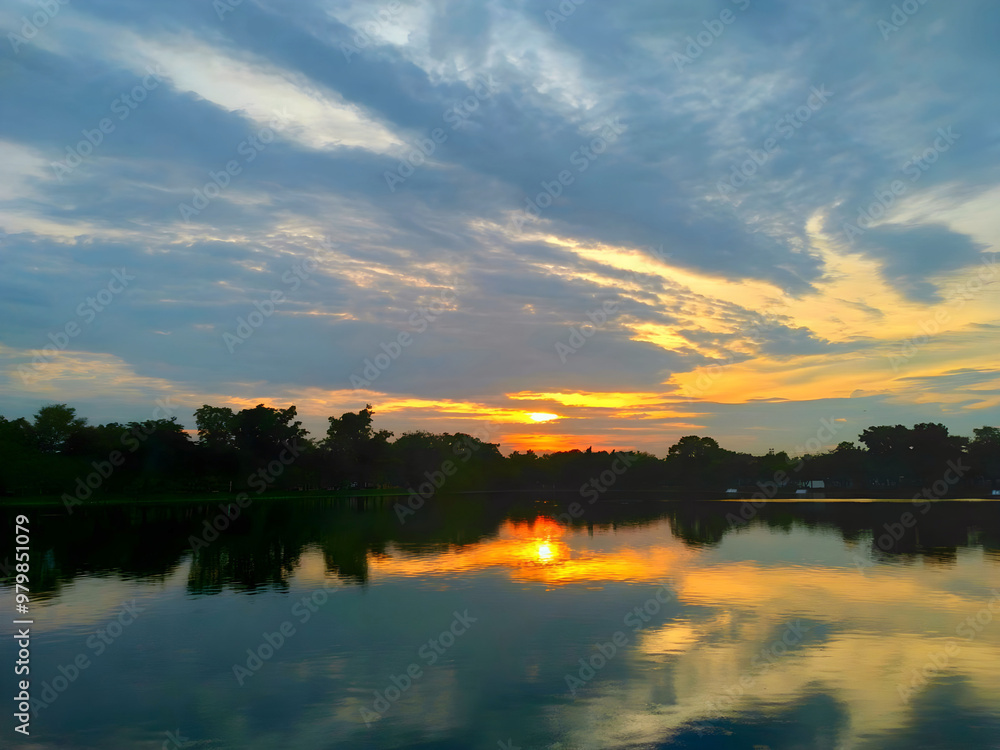 Obraz premium A sunset over a lake with a beautiful sky and trees in the background