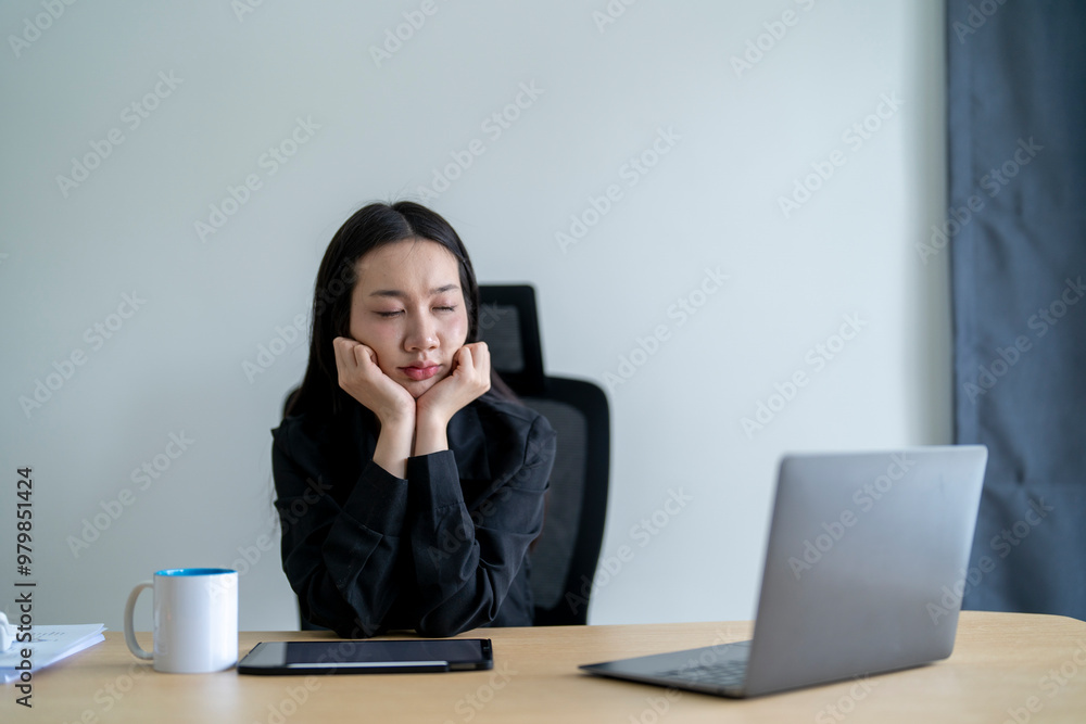 Asian businesswoman feeling tired and stressed from working with a laptop in office Asian businesswoman feeling tired and stressed from working with a laptop in office
