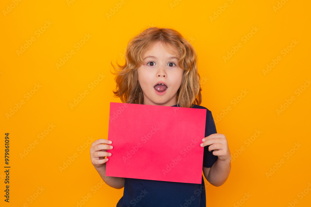 Kid with empty sheet of paper, isolated on yellow background. Portrait of a kid holding a blank placard, poster. Copyspace. Surprised face, amazed emotions of child. Kid with empty sheet of paper, isolated on yellow background. Portrait of a kid holding a blank placard, poster. Copyspace. Surprised face, amazed emotions of child.