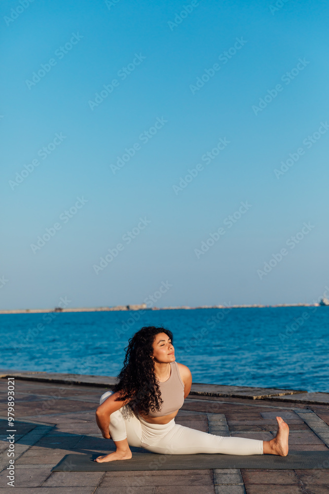 Athletic woman doing gymnastics yoga asana by the sea Athletic woman doing gymnastics yoga asana by the sea