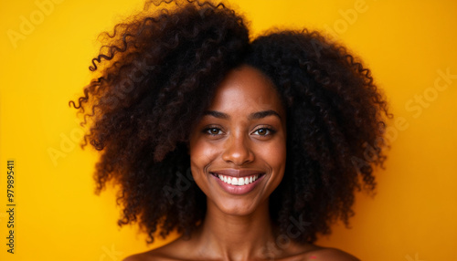 Portrait of a confident African American woman with curly hair, set against mustard yellow.