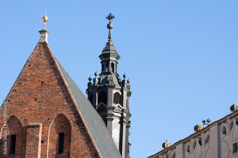 Fototapeta premium Beautiful church tower against a clear blue sky, showcasing intricate architecture. Features a pointed roof and decorative spire with a cross on top.