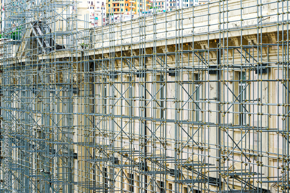 Assembly modern metal tube scaffolding around house facade before renovation works Assembly modern metal tube scaffolding around house facade before renovation works