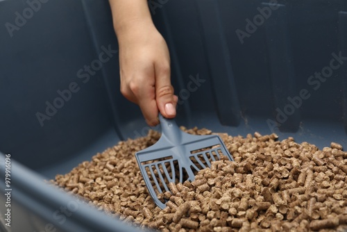 Woman cleaning cat litter tray with scoop, closeup photo