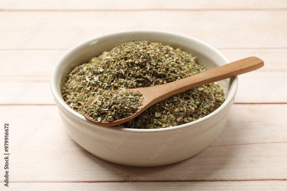 Dried oregano in bowl and spoon on wooden table, closeup Dried oregano in bowl and spoon on wooden table, closeup