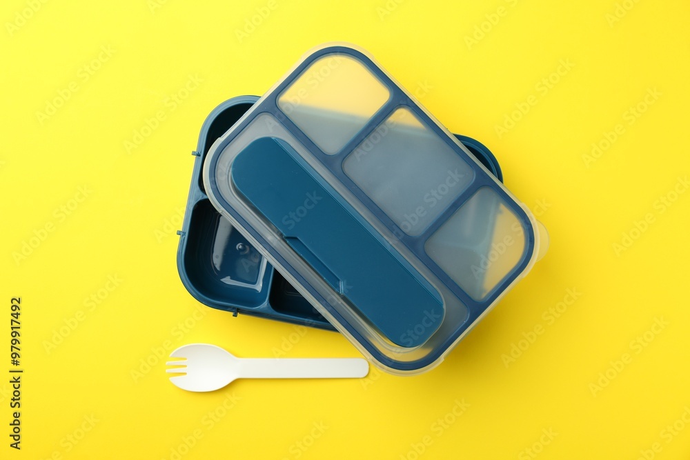 Empty lunch box and fork on yellow background, flat lay Empty lunch box and fork on yellow background, flat lay