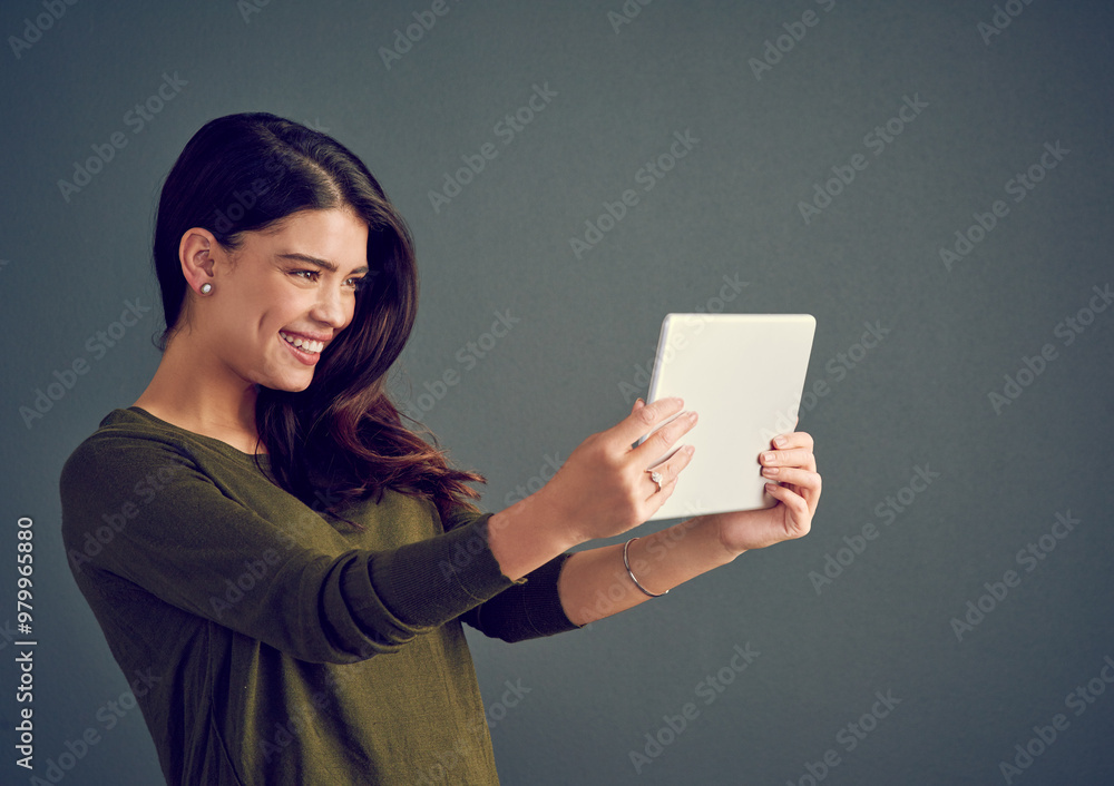 Naklejka premium Happy, woman and tablet in studio for video call, live stream and connectivity to internet. Influencer, smile and tech on gray background for selfie, follower interaction and social media update