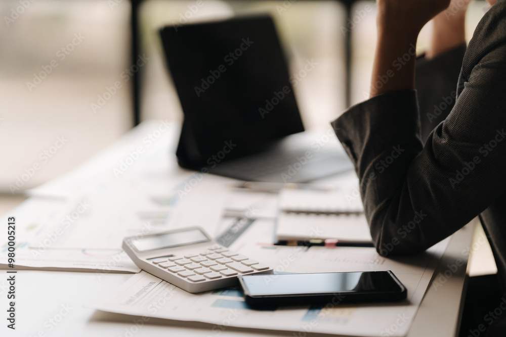 Businesswoman Analyzing Data: A close-up shot of a businesswoman's hands focused on analyzing data on a desk, with a calculator, smartphone, notebook, and a laptop in the background. The image evokes Businesswoman Analyzing Data: A close-up shot of a businesswoman's hands focused on analyzing data on a desk, with a calculator, smartphone, notebook, and a laptop in the background. The image evokes