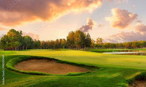Golf course at sunset with beautiful sky and sand trap. Picturesque panoramic view