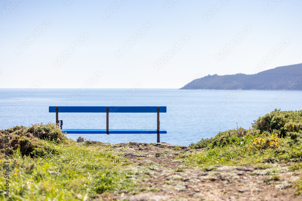 A blue bench overlooking the Galician coast with Cape Finisterre in the background A blue bench overlooking the Galician coast with Cape Finisterre in the background